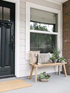 a bench sitting on the side of a building next to a black door and window