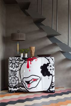 a white and black cabinet with red paint dripping down it's face on the wall