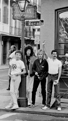 black and white photograph of four men standing on the sidewalk