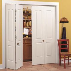 two white doors open in a kitchen with a red chair and yellow wall behind them