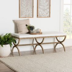 a white bench sitting on top of a wooden floor next to a potted plant