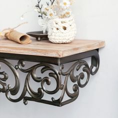 a wooden table topped with a white vase filled with flowers next to a candle holder