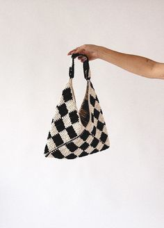 a hand holding a black and white bag with checkerboard pattern on the front