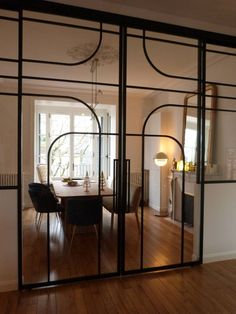 an open glass door leading to a dining room with wooden floors and chairs in it