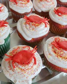 there are many cupcakes with white frosting and red crab decorations on them