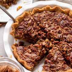 a pecan pie on a white plate with a slice cut out and ready to be eaten