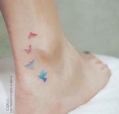 a woman's foot with colorful birds on the bottom of her leg and an arrow in the middle