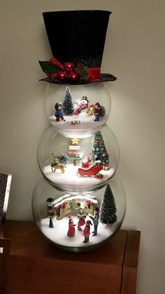 three snow globes with christmas decorations in them on top of a wooden table next to a wall