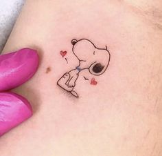 a woman's stomach with a small tattoo of a dog holding a heart on it