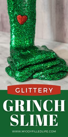 a green glitter boot sitting on top of a white marble counter next to a red heart