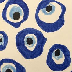 an artistic painting with blue circles and black dots on white paper that looks like eyeballs