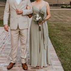 a man and woman standing next to each other on a brick walkway in front of a building