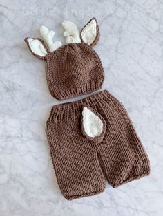 two knitted bunny hats and pants on a marble surface