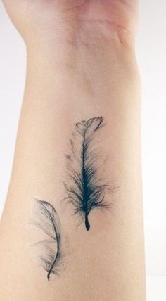 a feather tattoo on the back of a woman's arm