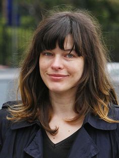 a close up of a person wearing a black shirt and long hair with bangs on her head