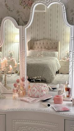 a bedroom with a large white vanity mirror and pink flowers on the wall next to it