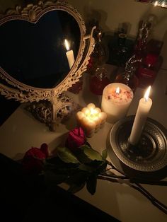 candles and roses on a table with a heart shaped mirror