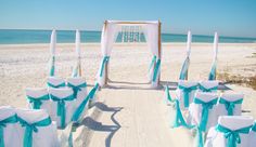 an outdoor wedding setup on the beach with blue sashes and white draping