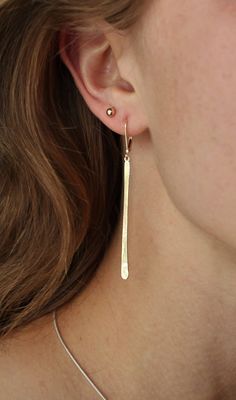 "These lovely earrings are handmade from 14k yellow recycled gold and are 2.25 \" total length from the top of the lever back wire. The long slender stick of gold hangs from a soldered circle for easy movement and style. I have used lever backs because they are very secure and comfortable to wear. The plain lever back compliments this modern design. They speak for themselves, not much to say but wow 3 grams total weight made with recycled 14k gold. Available in 14k white, yellow, or rose gold. M Gold Thread Earrings, Earring Bar, Long Bar Earrings, Trendy Stud Earrings, Earrings Dangle Simple, Gold Bar Earrings, Stick Earrings, Unusual Earrings, Bar Stud Earrings