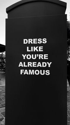 a black and white photo of a sign that says dress like you're already famous