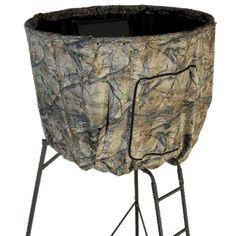 a large camouflage pot holder on top of a metal stand with legs and an open lid