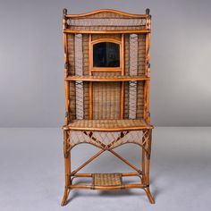 an old bamboo shelf with a mirror on top and wicker shelves below it, against a gray background