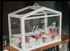 a glass box with flowers inside sitting on a table