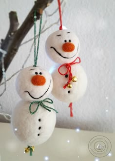 two snowman ornaments hanging from a tree