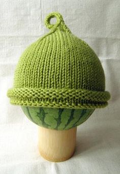 a green knitted hat sitting on top of a wooden head