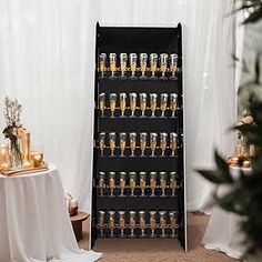 a display case filled with lots of glasses next to a white table cloth covered wall