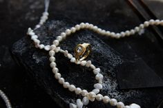 a necklace with pearls and a gold clasp on it sitting on top of a rock