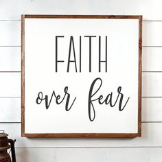 a sign that says faith over fear on the side of a wall next to a lantern