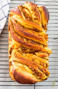 a loaf of bread with meat and cheese on it sitting on a cooling rack next to a towel