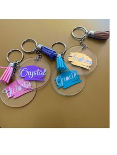 three acrylic keychains with name tags attached to them on a table