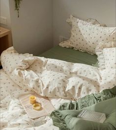 an unmade bed with green sheets and pillows on top of it next to a book