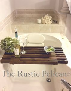 a bath tub with a wooden tray holding wine bottles and flowers on the ledge next to it