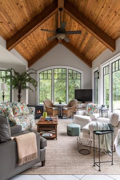 a living room filled with lots of furniture under a wooden ceiling mounted flat screen tv