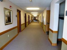 an empty hallway with paintings on the walls and carpeting in front of it,