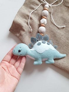 a hand is holding a small toy dinosaur on a piece of fabric next to a t - shirt