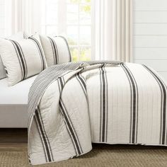 a white bed with black and white striped comforter in front of a large window