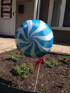 a large blue and white balloon with a red bow on it's end in front of a house