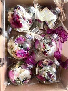 six ornaments in a box with ribbons and bows on the top one is filled with flowers