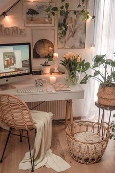 a white desk topped with a computer monitor next to a basket filled with flowers and candles