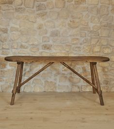 a wooden table sitting on top of a hard wood floor next to a stone wall