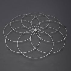 a circular metal object on a gray surface with white wire in the shape of a flower