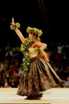 a woman in a hula skirt is dancing on the court with her hands up