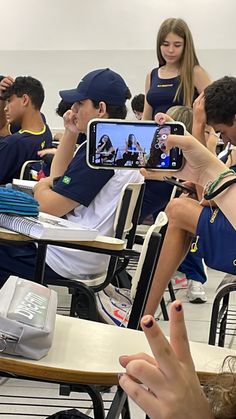 a group of young people sitting at desks with cell phones in front of them