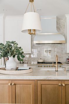 a kitchen with marble counter tops and wooden cabinets, along with a white lamp hanging from the ceiling