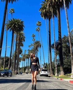 a woman is walking down the street with her skateboard in hand and palm trees behind her