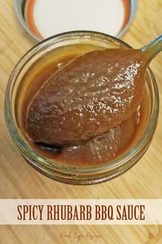 a jar filled with bbq sauce sitting on top of a wooden table next to a spoon